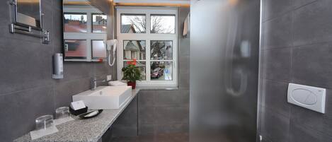 A modern bathroom with a large mirror, a sink, and a toilet.