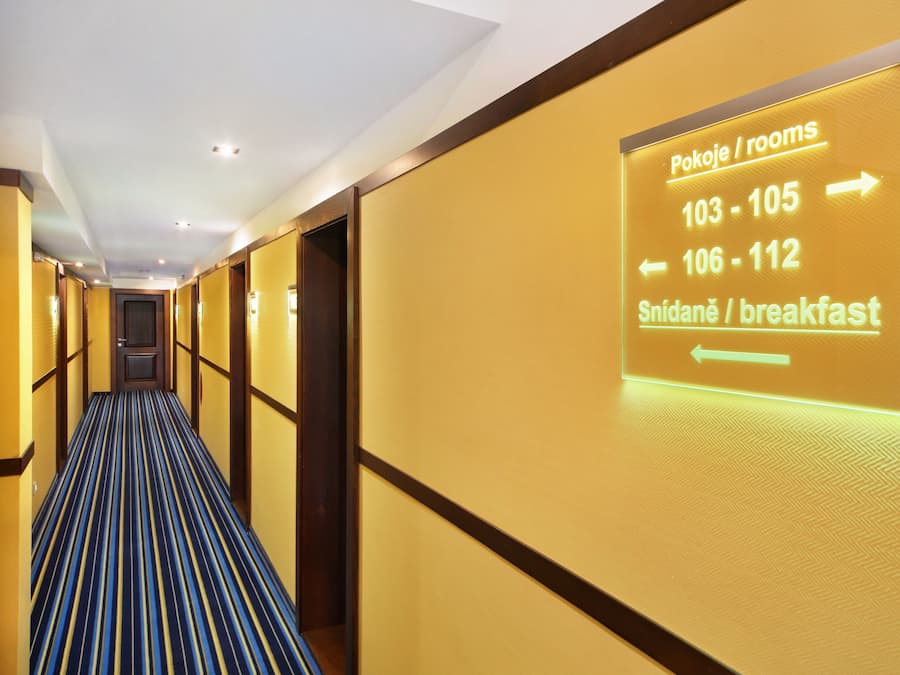 Un pasillo de hotel con señales que indican los números de habitación y un área para el desayuno.