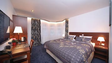Una habitació d'hotel amb un llit gran, dues taules de nit amb làmpades, un escriptori amb un telèfon i una cadira.