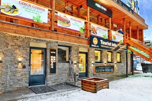 Un hotel con fachada de piedra, balcones de madera y varios carteles que anuncian comida local e información turística.