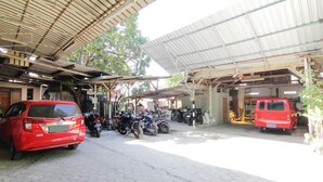 Uma área de estacionamento coberta com várias motocicletas e um carro vermelho.