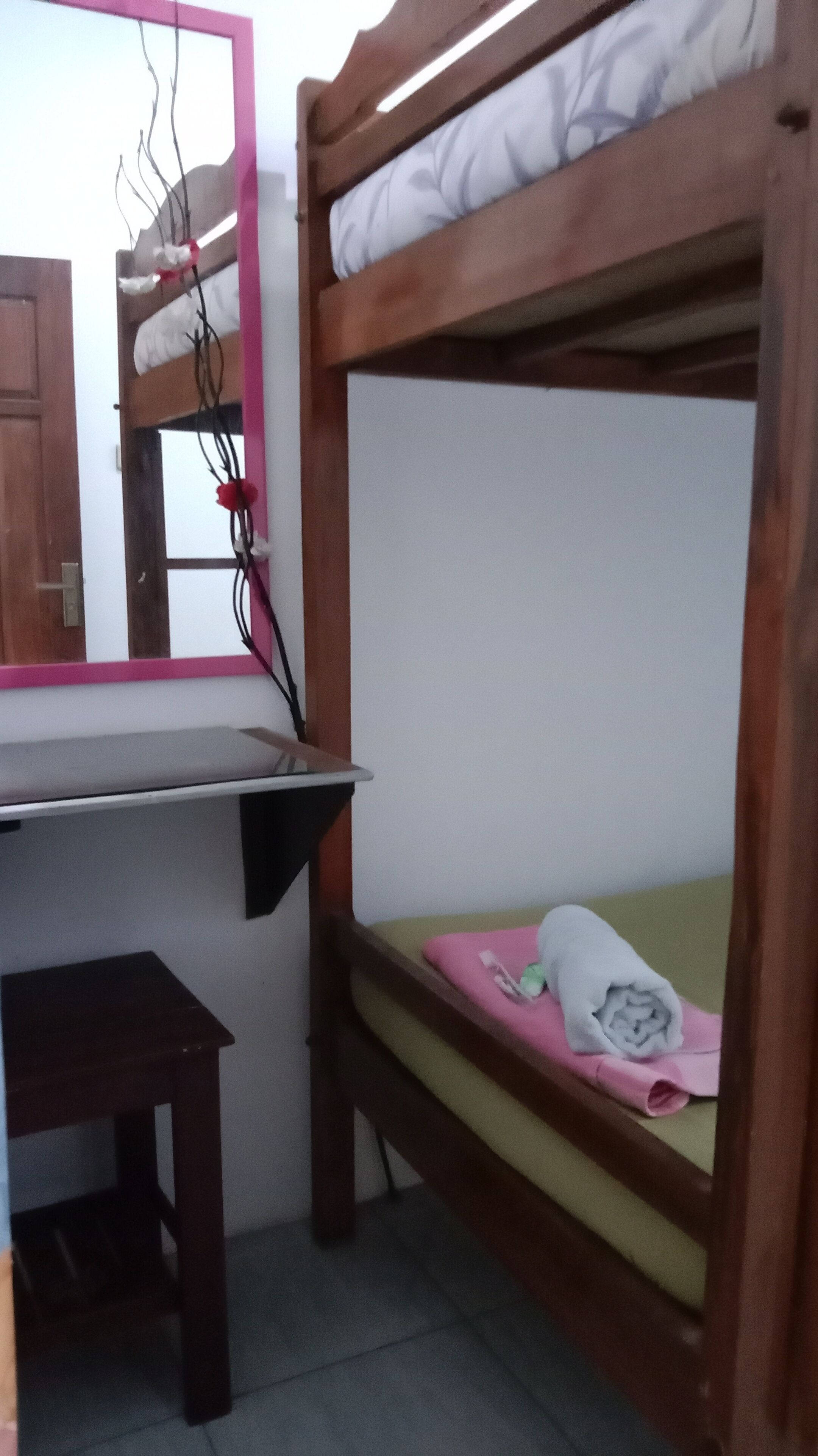 Un lit superposé avec un bureau et une chaise, un miroir et une petite table.