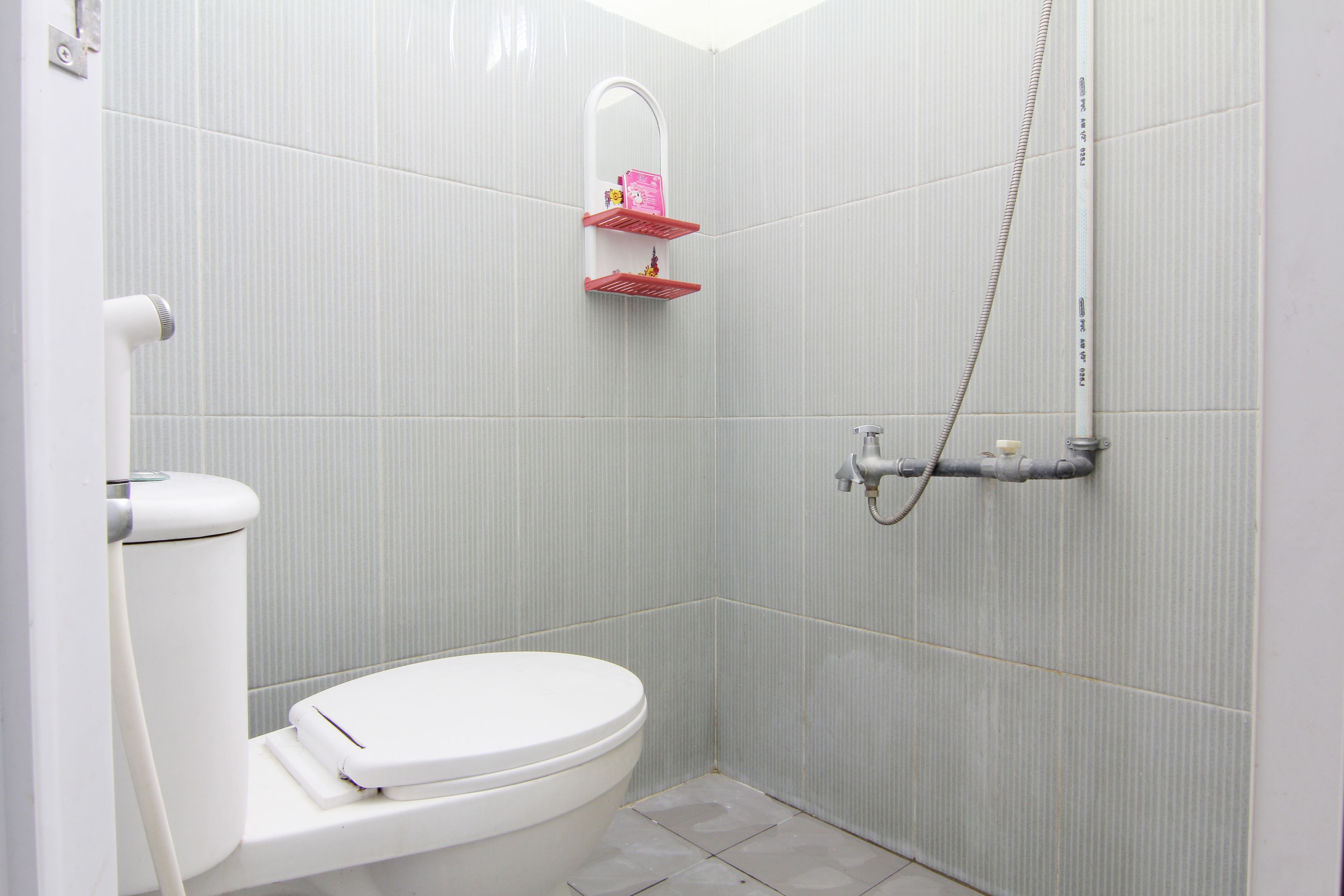 Un baño pequeño y moderno con inodoro, ducha y espejo.