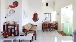 Uma sala de estar com sofá, cadeiras, mesa de centro e estante de livros.