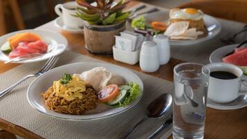 A table with plates of food, a water pitcher, salt and pepper shakers, and a cup of coffee.