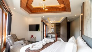 Una habitación de hotel moderna con una cama grande, un sofá, un televisor y un techo de madera.