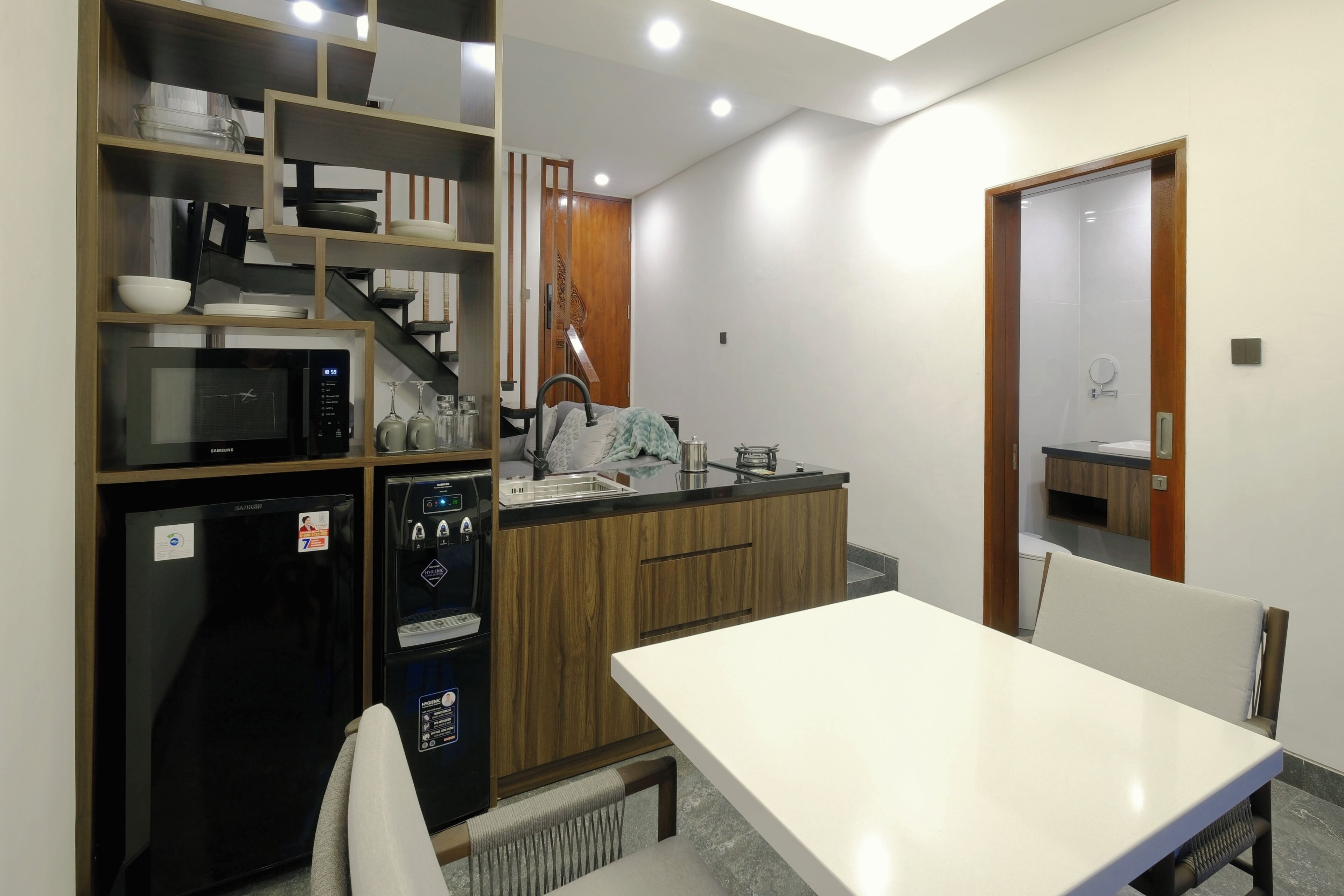 Eine moderne Küche mit Mikrowelle, Kühlschrank und eingebautem Backofen. Es gibt einen Esstisch mit Stühlen und eine Holzkommode mit Regalen.