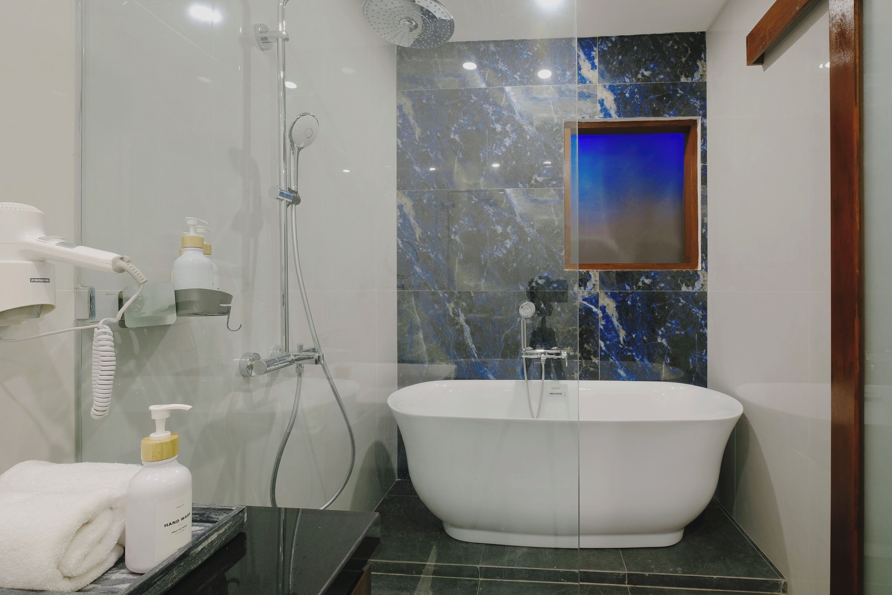 Un baño moderno con una bañera independiente, una ducha con cerramiento de vidrio y un tocador con espejo.