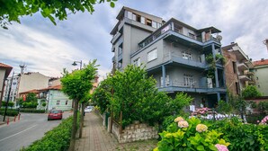 A multi-story residential building with balconies and a paved sidewalk. - Kerem Apart Pansiyon (Amasra)