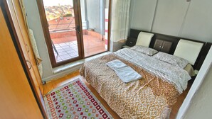 A bedroom with a large bed, a view through a sliding door to an outdoor area, and a small rug on the floor. - Kerem Apart Pansiyon (Amasra)