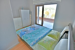 A bedroom with a bed, a wardrobe, and a balcony with a view. - Kerem Apart Pansiyon (Amasra)