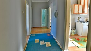 A hallway with a blue carpet, a ceiling fan, and a kitchen area with cabinets and a stove. - Kerem Apart Pansiyon (Amasra)