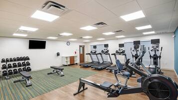 A gym with treadmills, elliptical machines, and a rack of dumbbells.