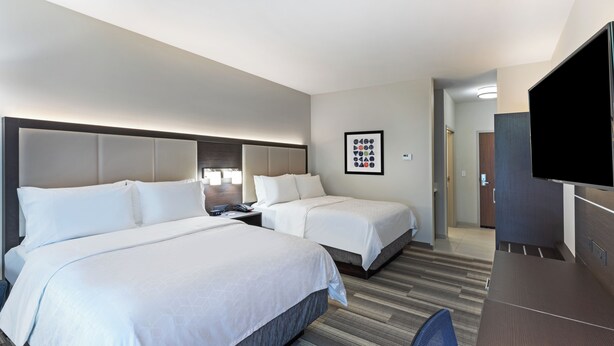 A hotel room with two beds, a desk, a TV, and a framed picture on the wall. - Holiday Inn Express & Suites Purcell by IHG (Purcell)
