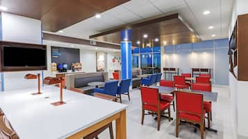 A modern cafe with a flat-screen TV, seating areas, and a coffee machine.
