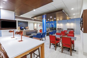 A modern cafe with a flat-screen TV, seating areas, and a coffee machine. - Holiday Inn Express & Suites Purcell by IHG (Purcell)