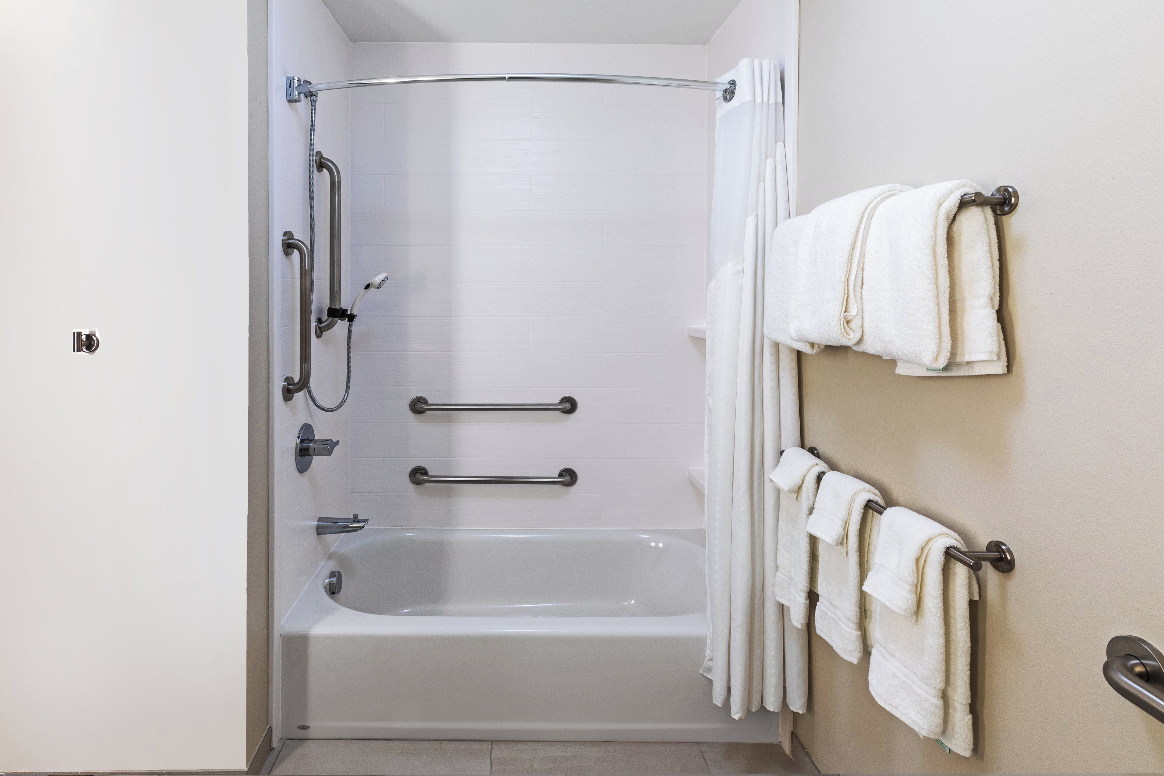 Een moderne badkamer met een inloopdouche, handgrepen en een handdoekrek.