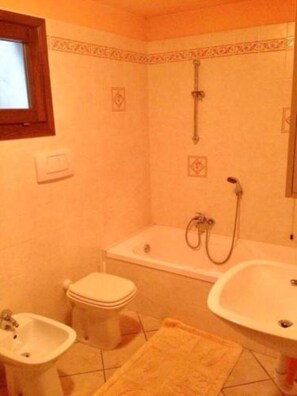 Ein Badezimmer mit einer Badewanne, einer Toilette, einem Bidet und einem Waschbecken.