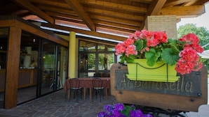 Un espace extérieur aménagé avec une pergola en bois, une table et des chaises, ainsi qu’une enseigne indiquant « Alberesea ».