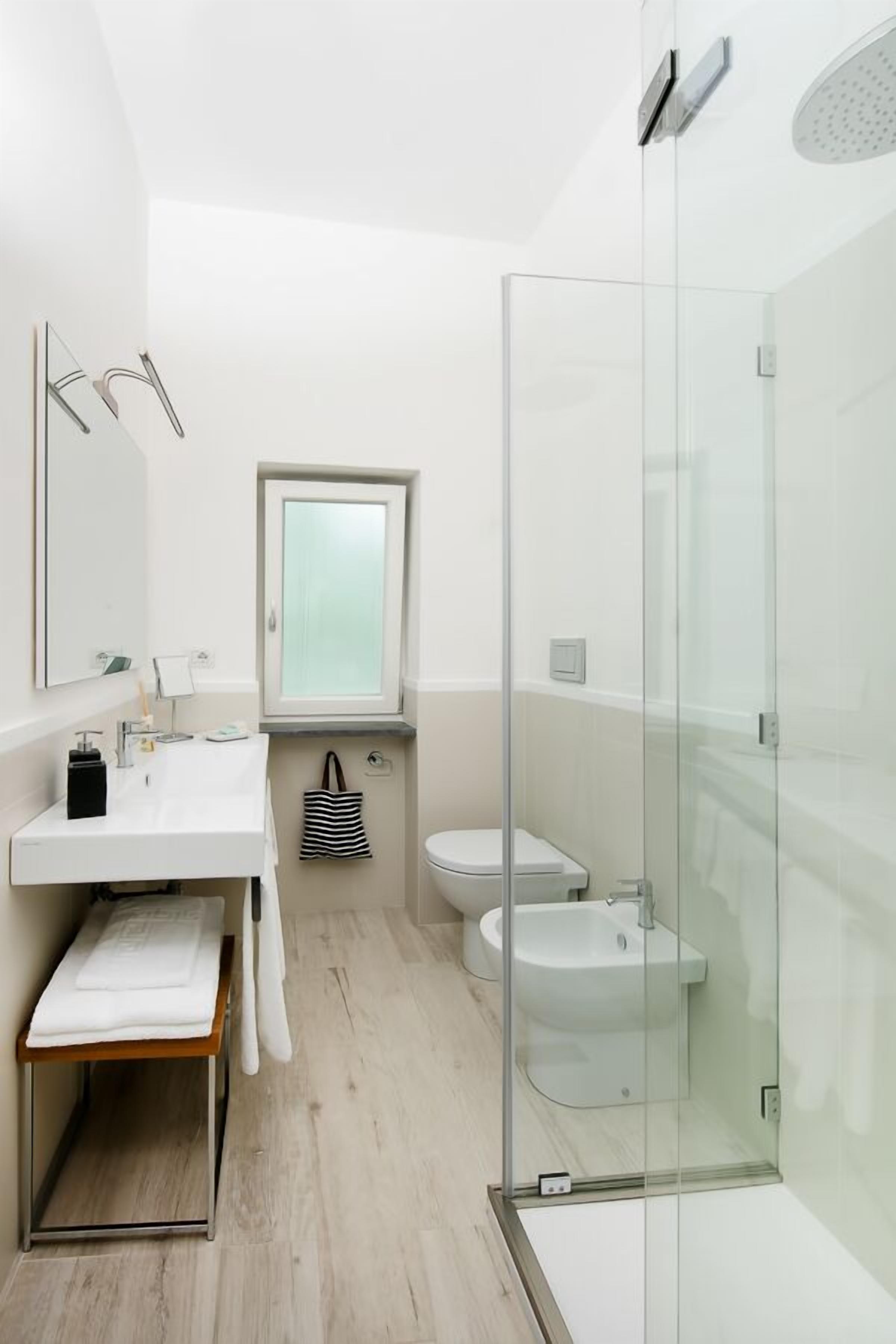 Un baño moderno con cabina de ducha de vidrio, un lavabo blanco y un inodoro.