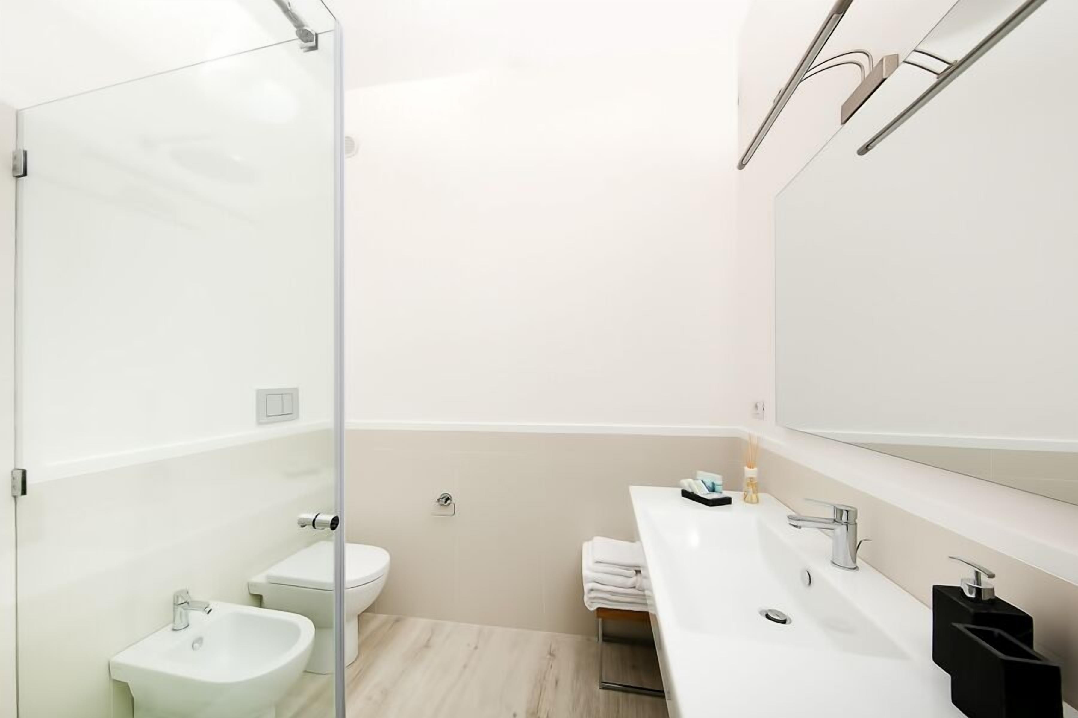 A modern bathroom with a glass shower enclosure, a white sink, and a large mirror.