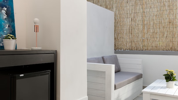 A compact room with a built-in seating area, a small table, and a potted plant. - Fuorlovado 40 (Capri)