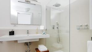 A modern bathroom with a large mirror, white sink, and a glass-enclosed shower. - Fuorlovado 40 (Capri)