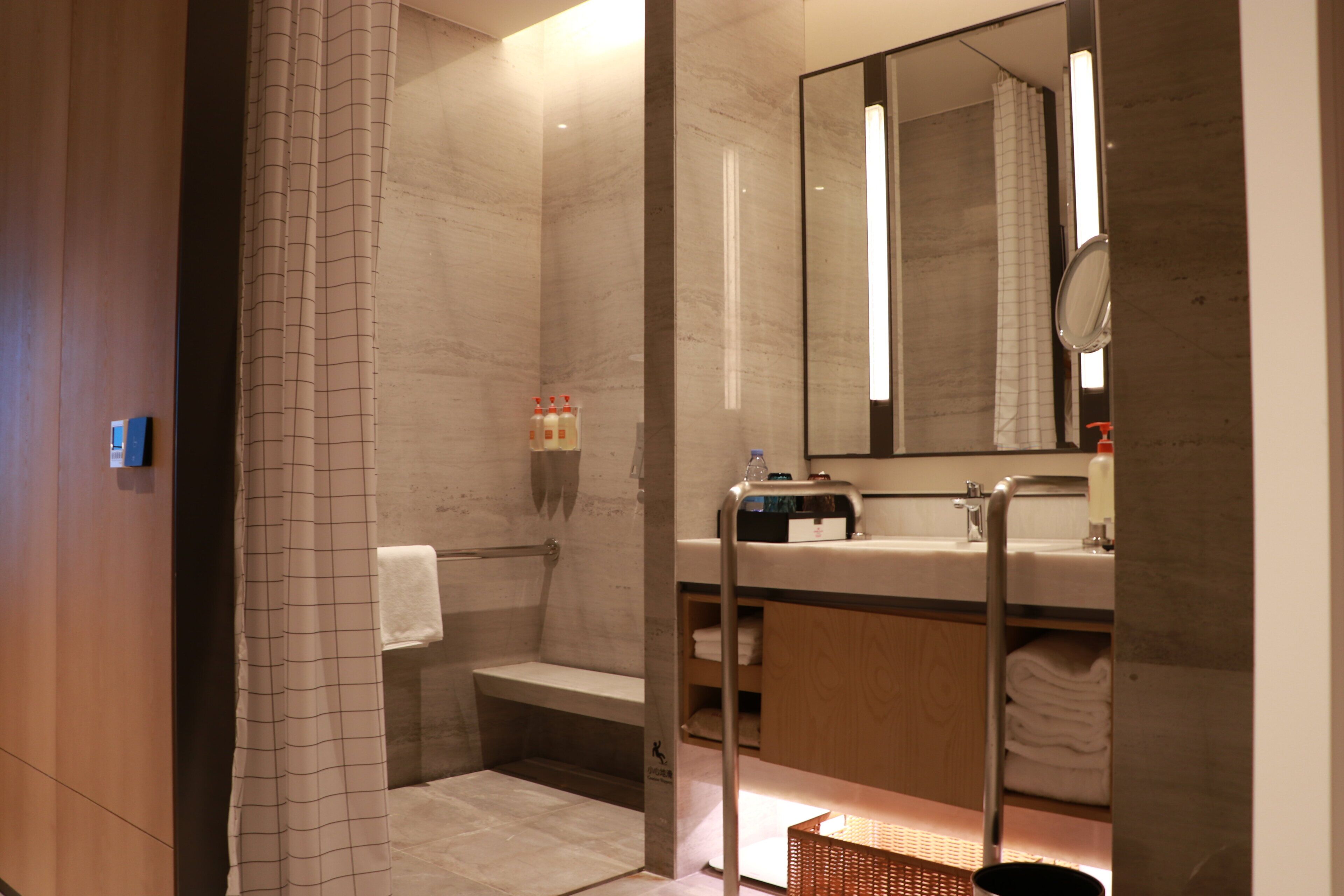 A modern bathroom with a shower, a sink, a mirror, and a towel rack.
