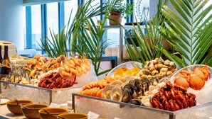 En seafoodbuffet med forskellige typer skaldyr og fisk anrettet på is, sammen med skåle og bestik.