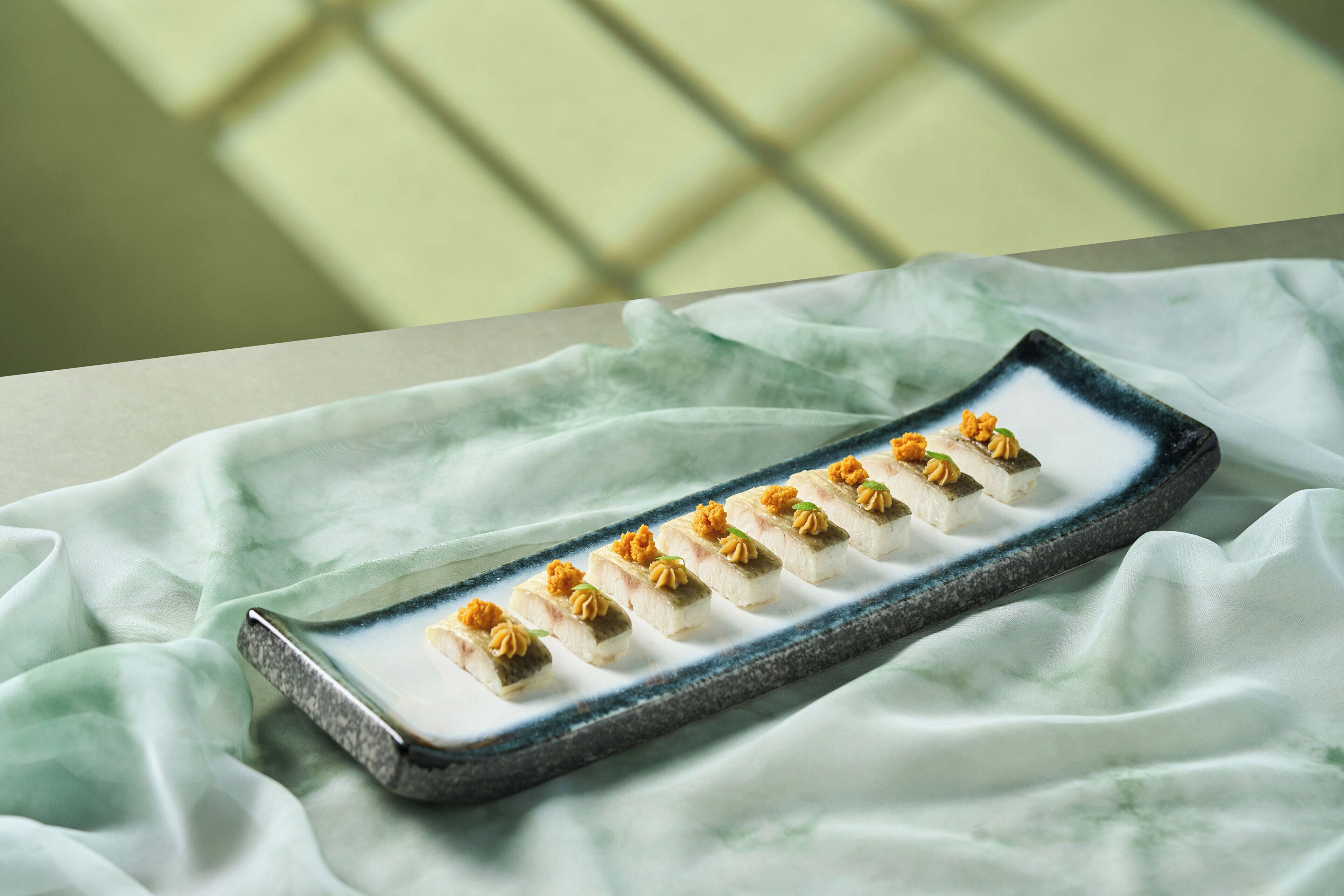 Un plato rectangular con comida sobre un mantel.