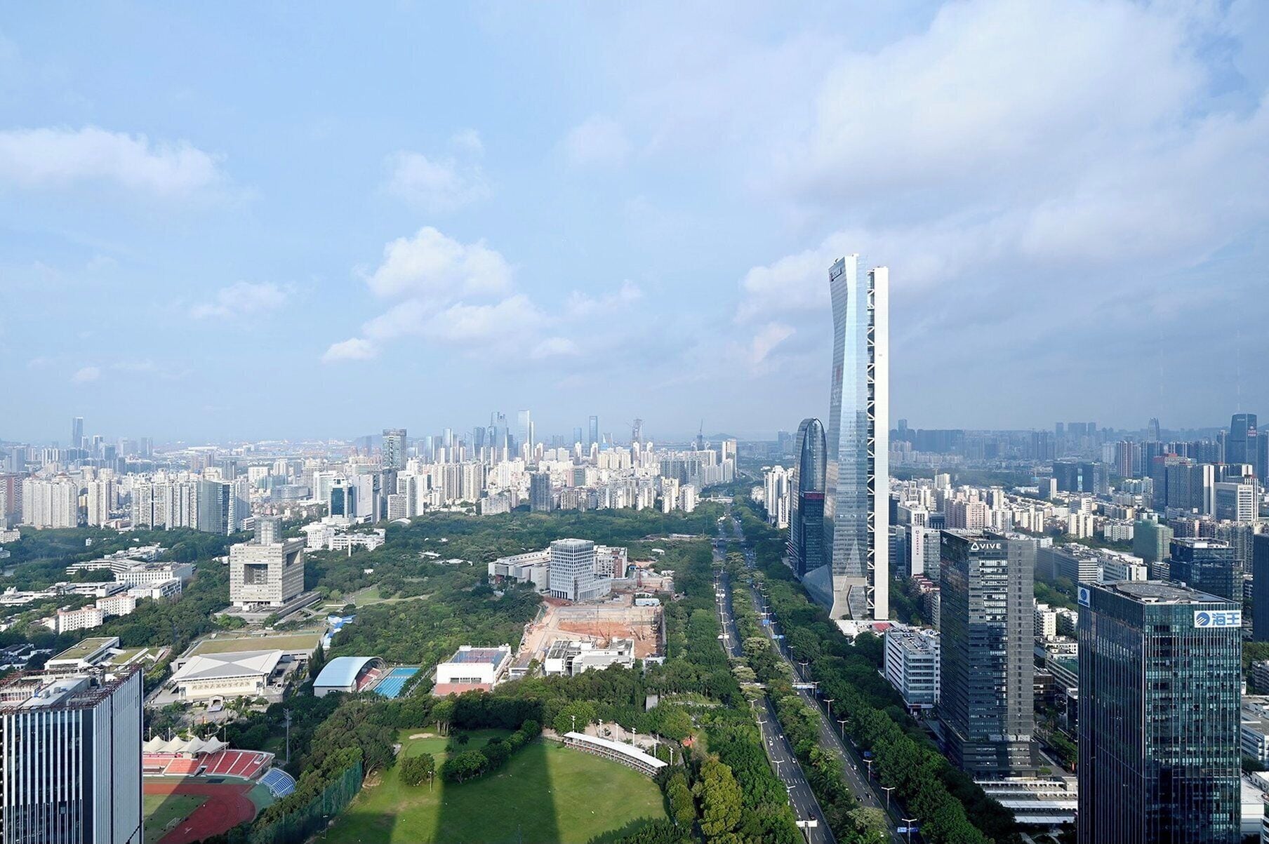 A high-rise building with a modern glass facade, surrounded by a dense urban area with other high-rise buildings.