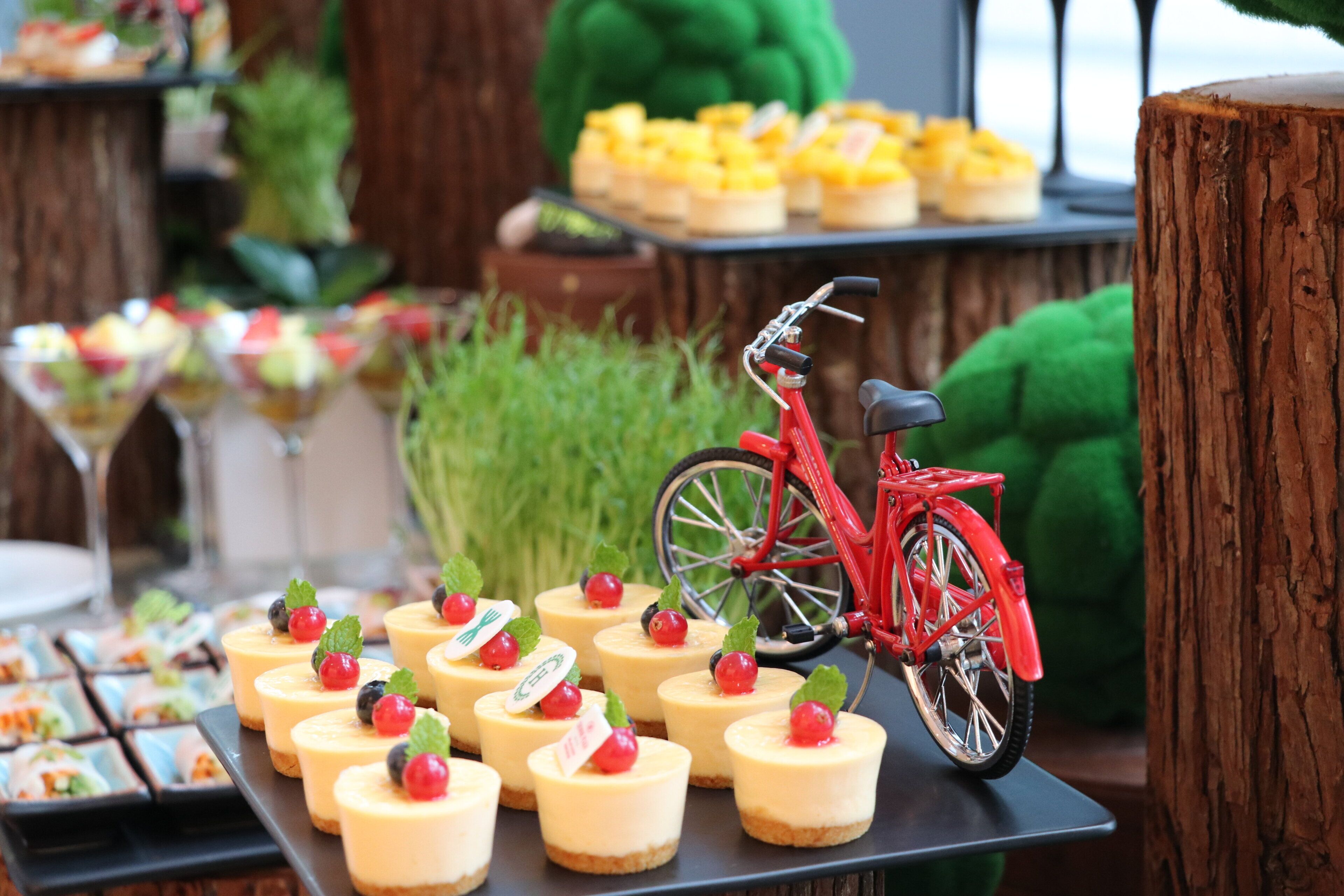 A dessert table with mini cheesecakes and a red bicycle.