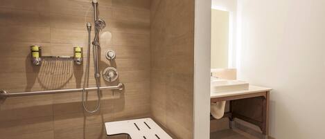 A shower area with a grab bar, a towel rack, and a showerhead.