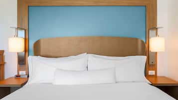 A neatly made bed with white linens, a wooden headboard, and two bedside lamps.
