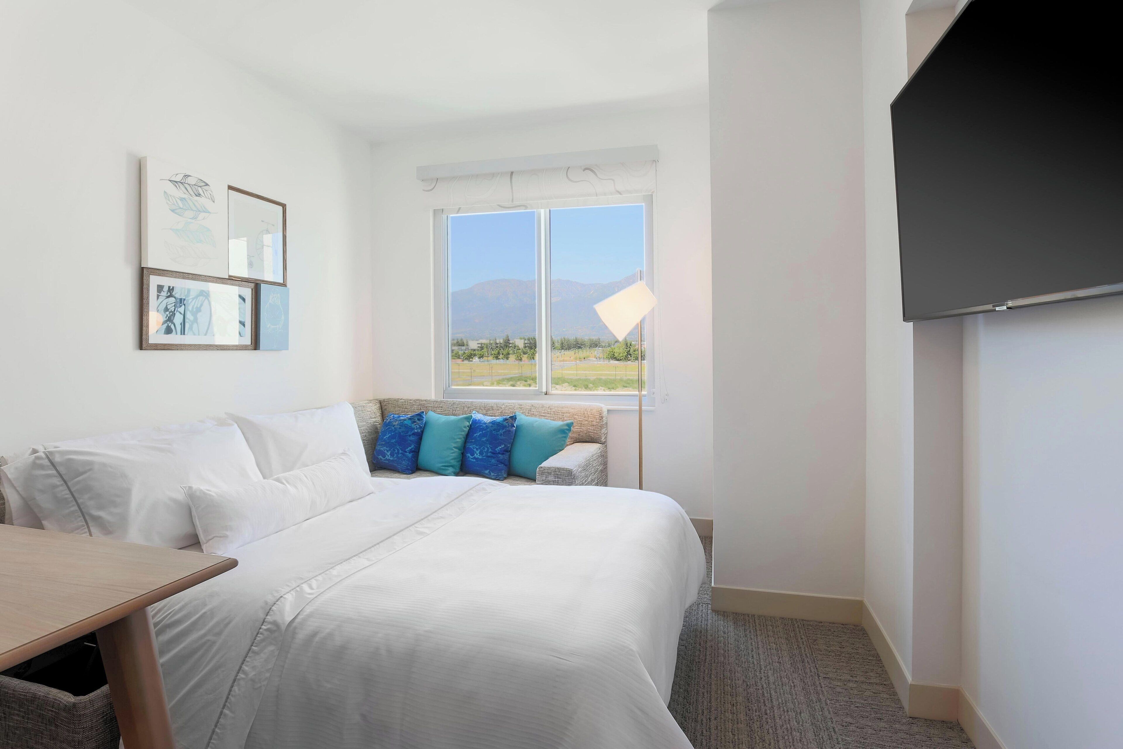 Ein Hotelzimmer mit Bett, Schreibtisch, Fernseher und Fenster mit Bergblick.