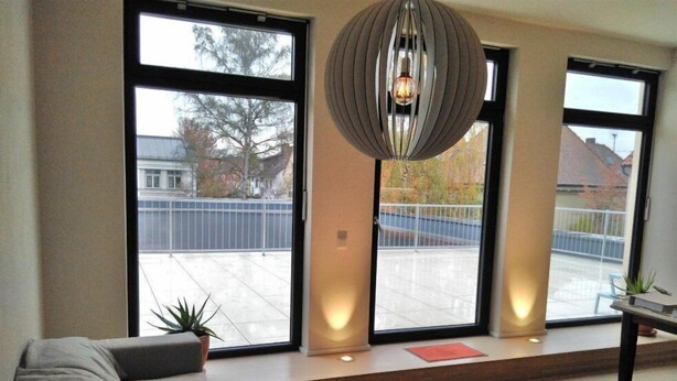 A modern living room with a large sofa, a coffee table, and a hanging light fixture.