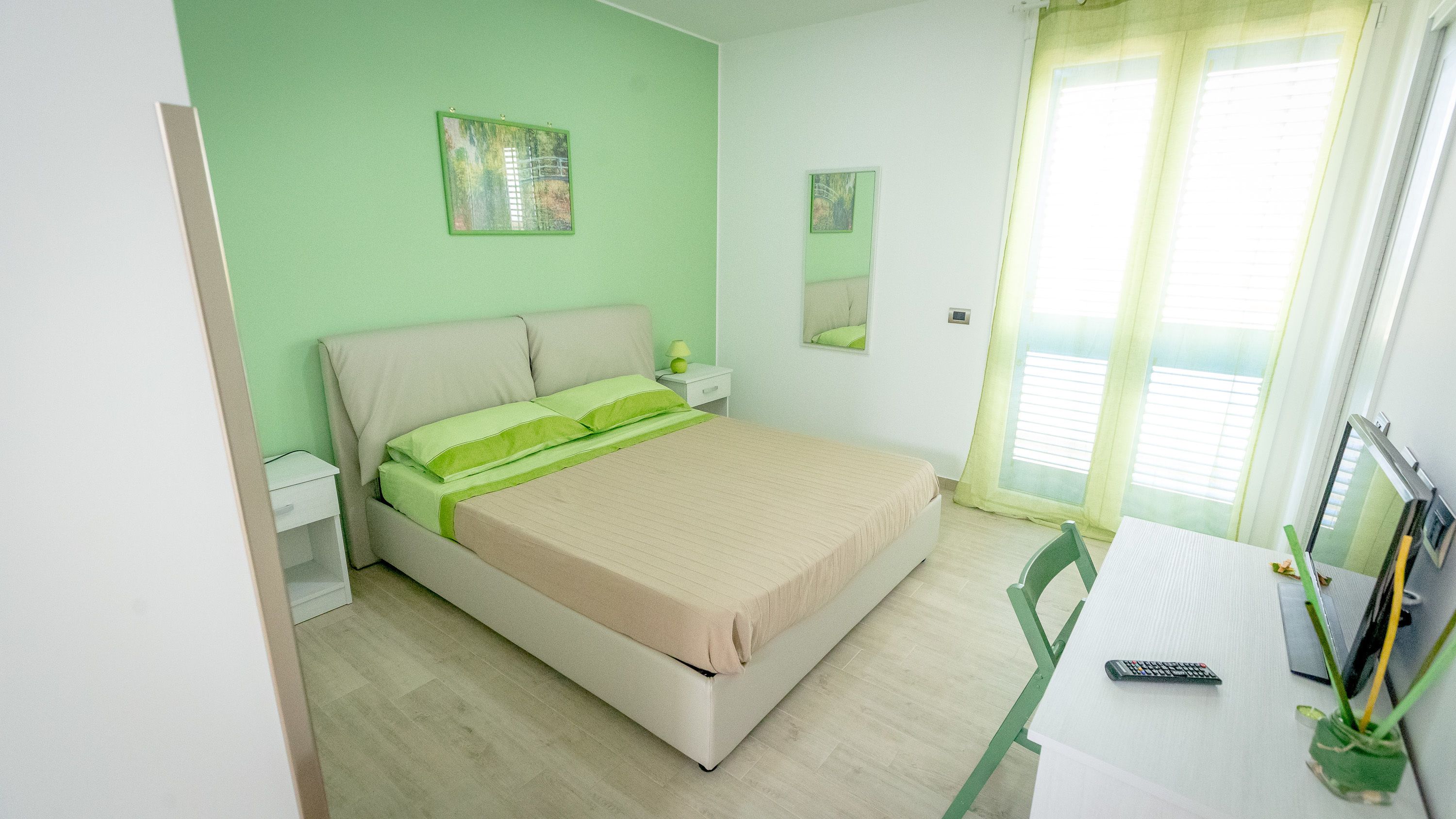 A bedroom with a bed, bedside tables, a desk, and a chair.