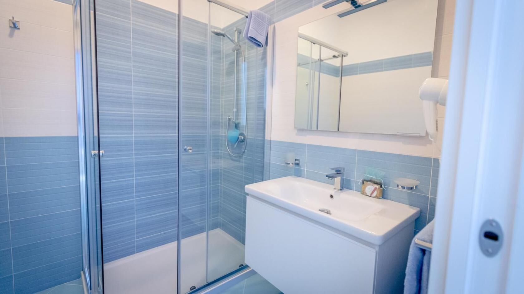 A modern bathroom with a glass-enclosed shower, a white sink, and a mirror above the sink.
