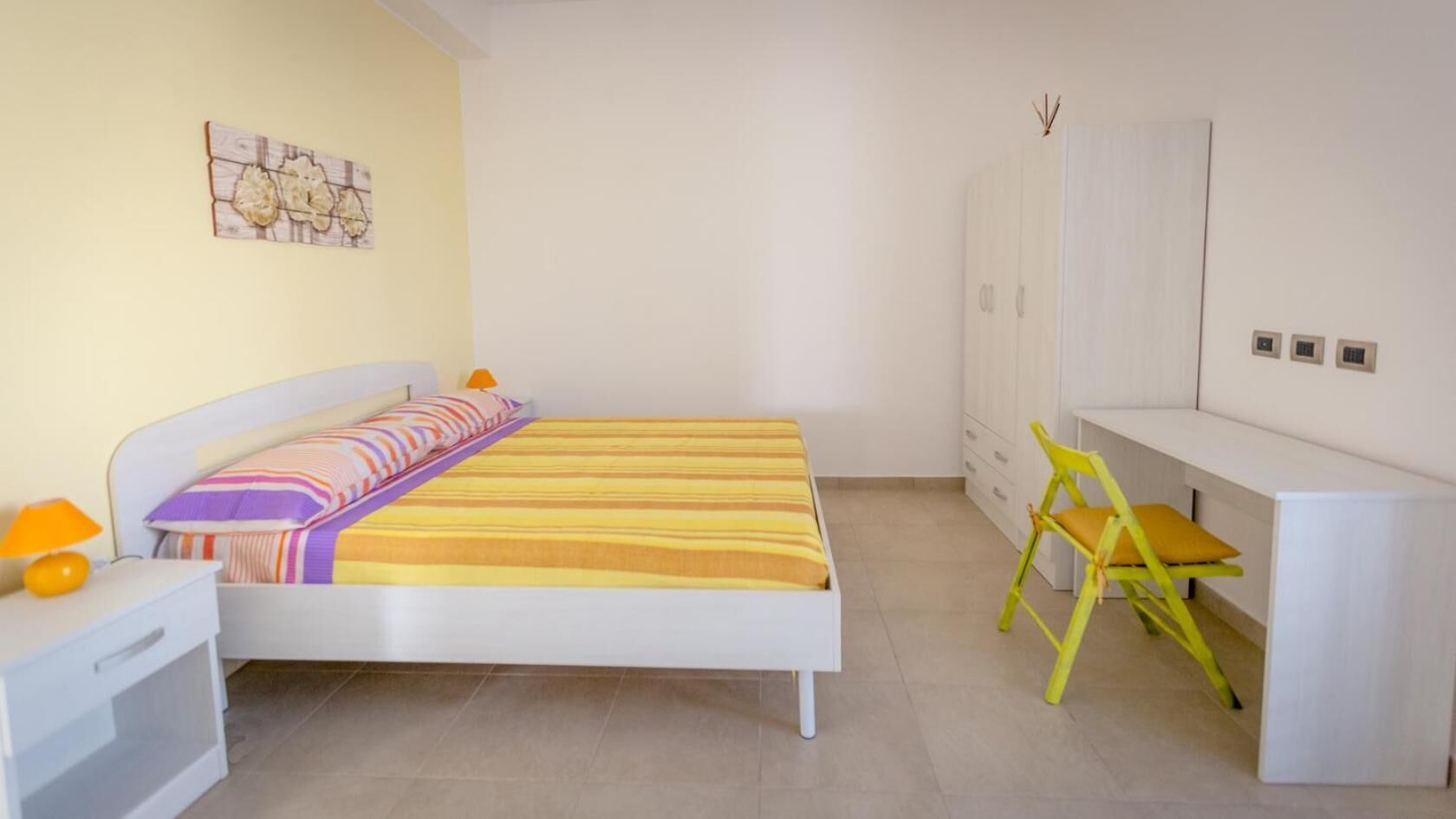 Una camera da letto con un letto, una scrivania, una sedia e un armadio.