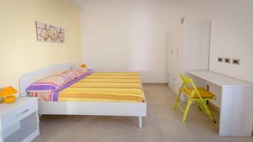 Una camera da letto con un letto, una scrivania, una sedia e un armadio.