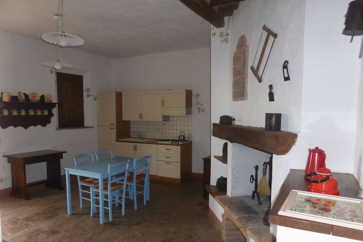 Eine kompakte Küche mit Essbereich, ausgestattet mit Holzschränken, einer gefliesten Spritzschutzwand und einem kleinen Spülbecken.