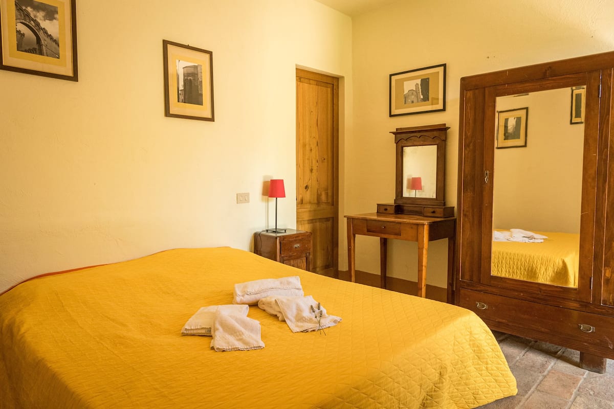 Ein Hotelzimmer mit einem großen Bett, einem hölzernen Schminktisch, einem Spiegel und gerahmten Bildern an der Wand.