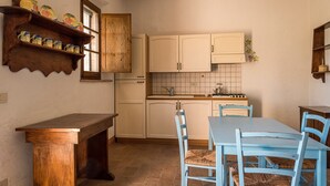 Une cuisine avec des meubles de rangement en bois, un pare-feu en carrelage et une table à manger entourée de chaises bleues.