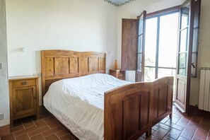 Cozy retreat with a comfortable bed, wooden nightstand, and a window offering a view of the outdoors.