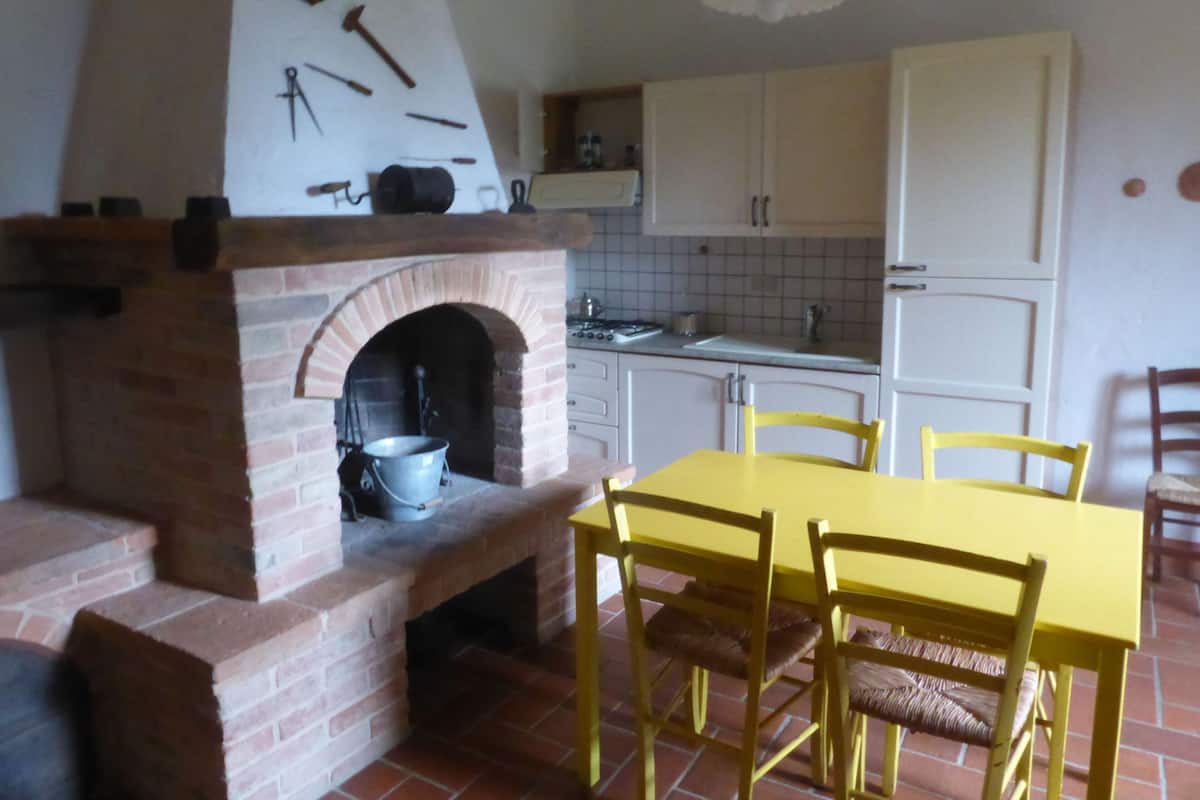 Eine Küche mit Backofen, weißen Schränken, einem gelben Tisch und Holzstühlen.