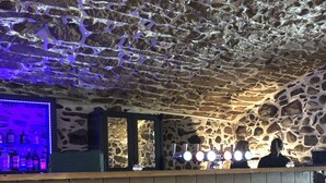 A bar area with a stone ceiling, wooden bar counter, and stools. - Marco Polo Business Apartments Sonne - Bremgarten (Bremgarten)