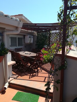 An outdoor patio with a table and chairs, surrounded by a pergola and potted plants. - B&B Le Terrazze (Crotone)