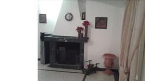 Una habitación con chimenea, una pequeña mesa con un florero y una cortina.