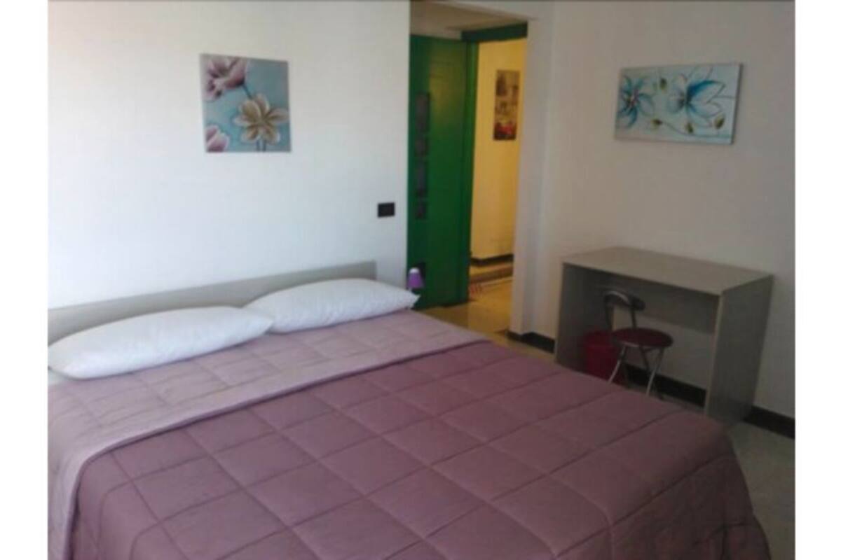 A bedroom with a bed, pillows, a desk, and a chair.