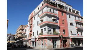 Un edificio de varios pisos con balcones, una tienda en la planta baja y un cielo azul despejado.